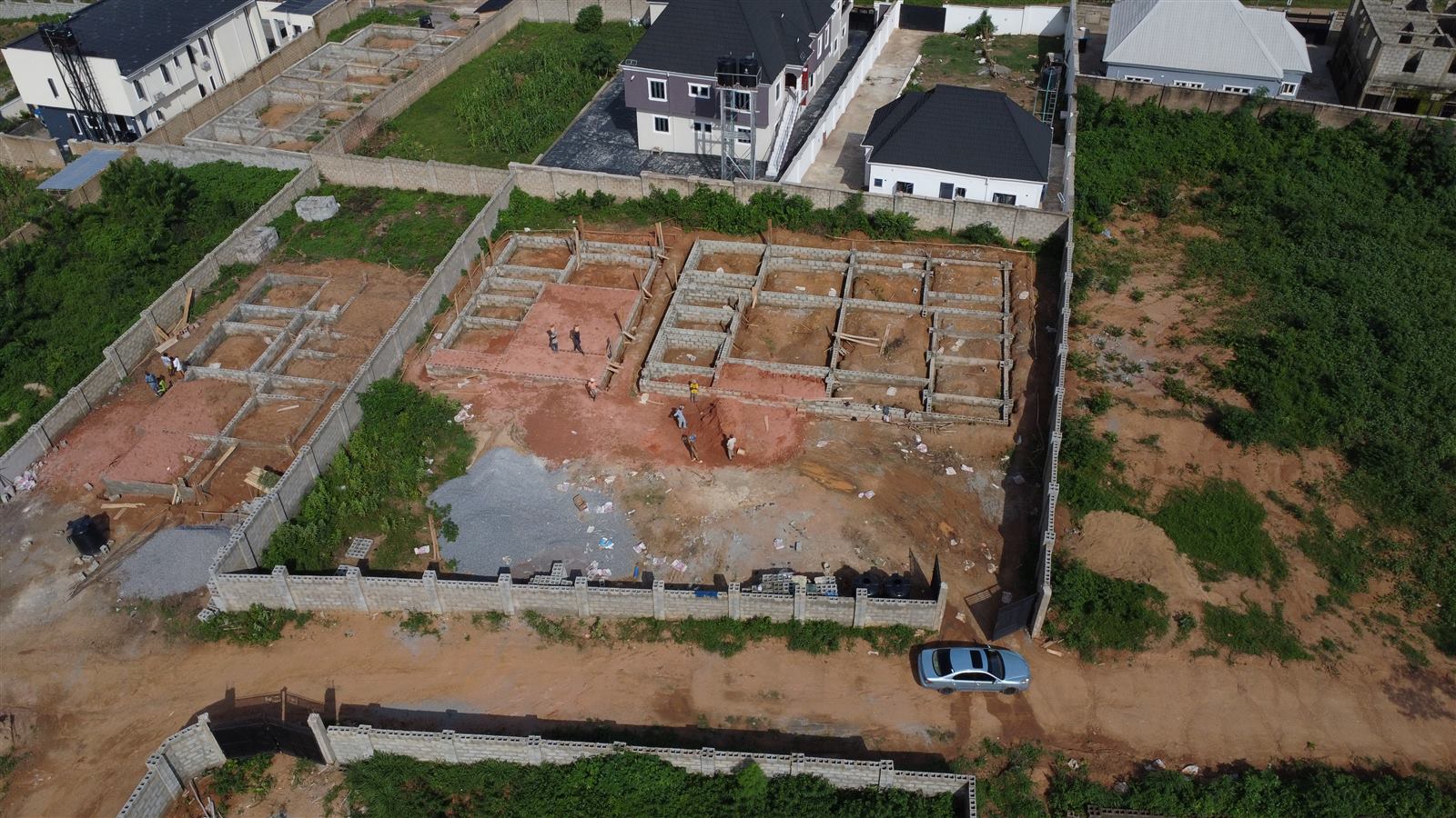 Aerial view of the Eden site at week 4: foundation walls at damp-proof course level with laterite backfilling underway in the rooms