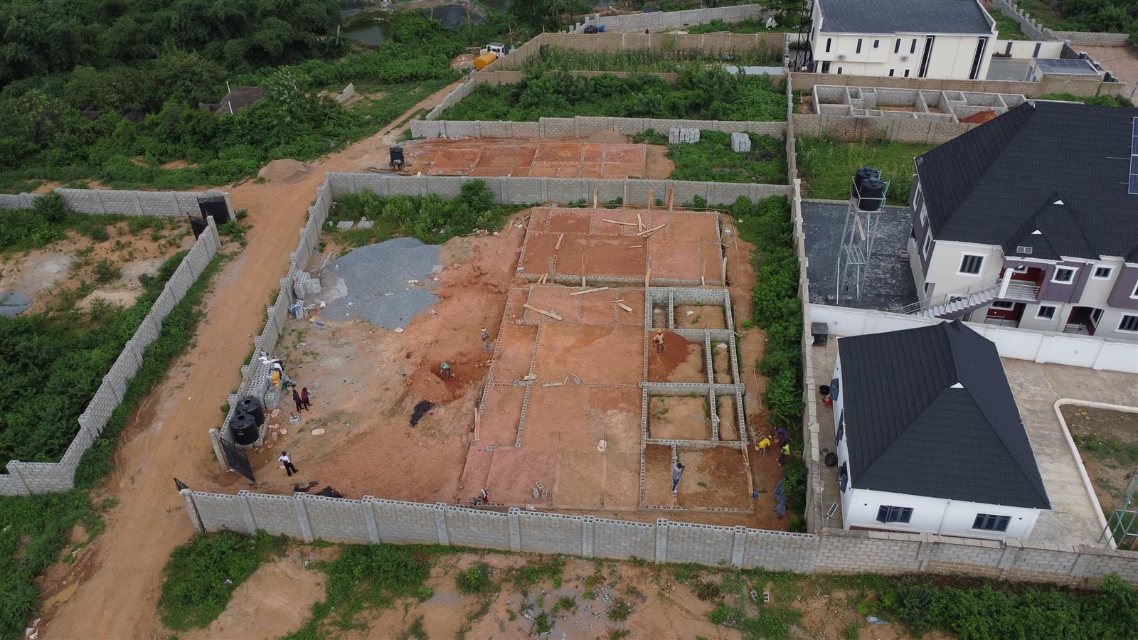 Aerial view of the Eden site at weeks 5 and 6: all three foundations backfilled with laterite and compacted, ready for the ground floor slabs