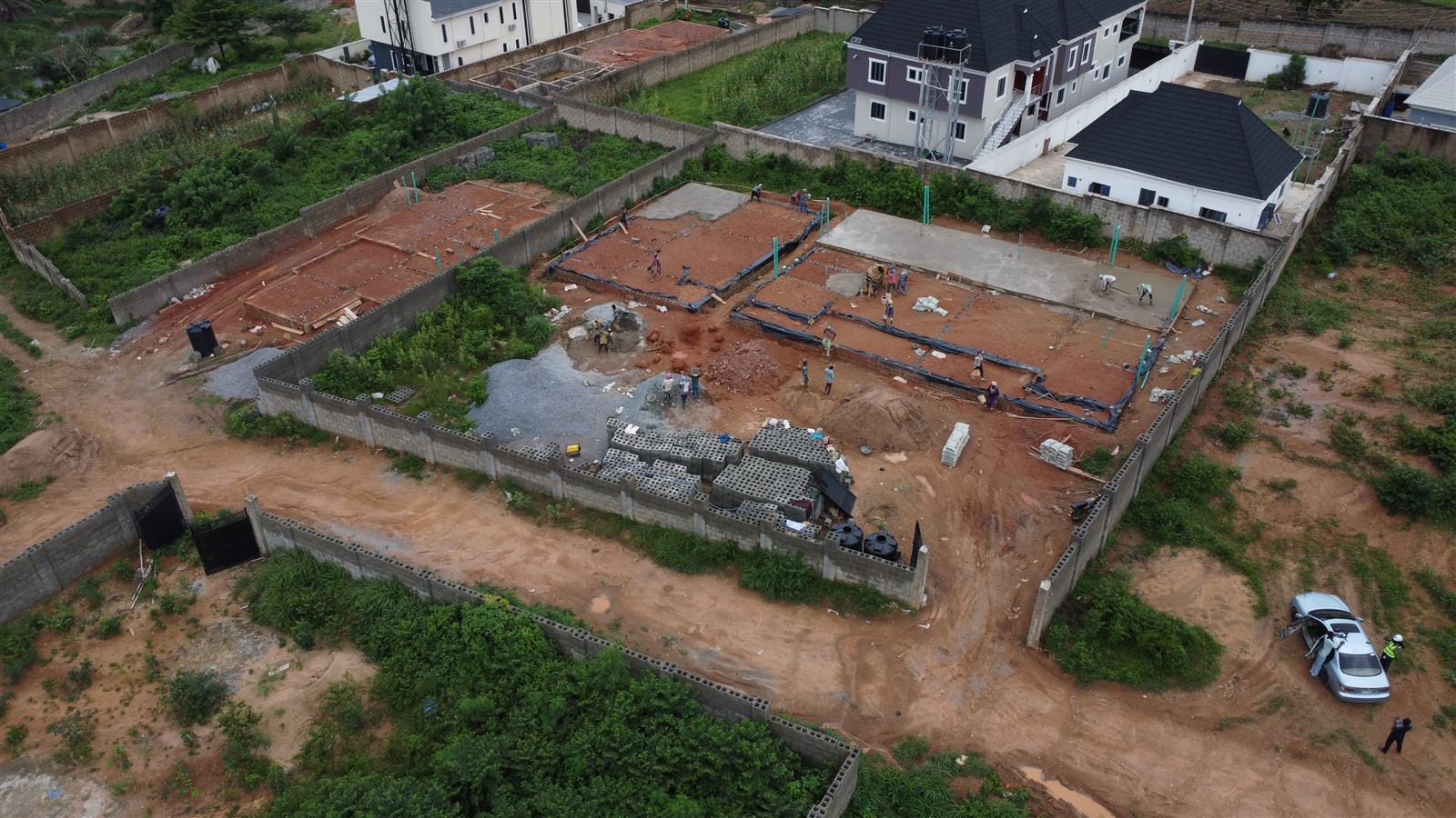 Aerial view of the Eden site at weeks 7 and 8: damp-proof membrane laid and concrete ground-floor slabs being cast across the three homes